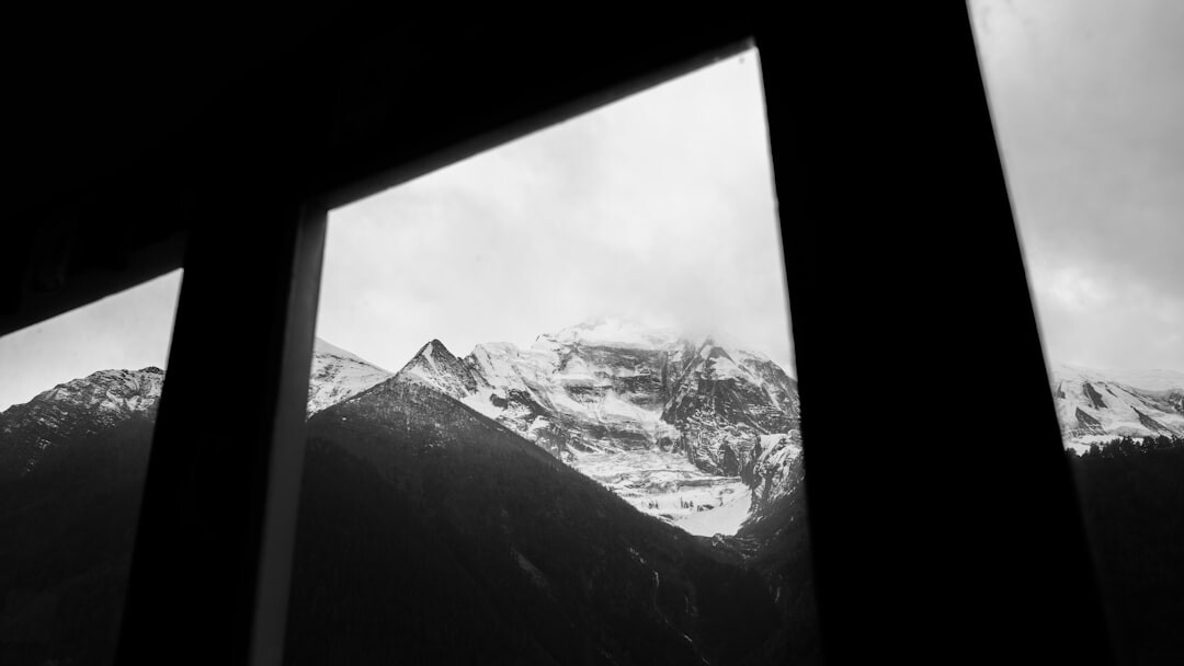 Close-up of hands typing on a laptop with a mountain view through the window